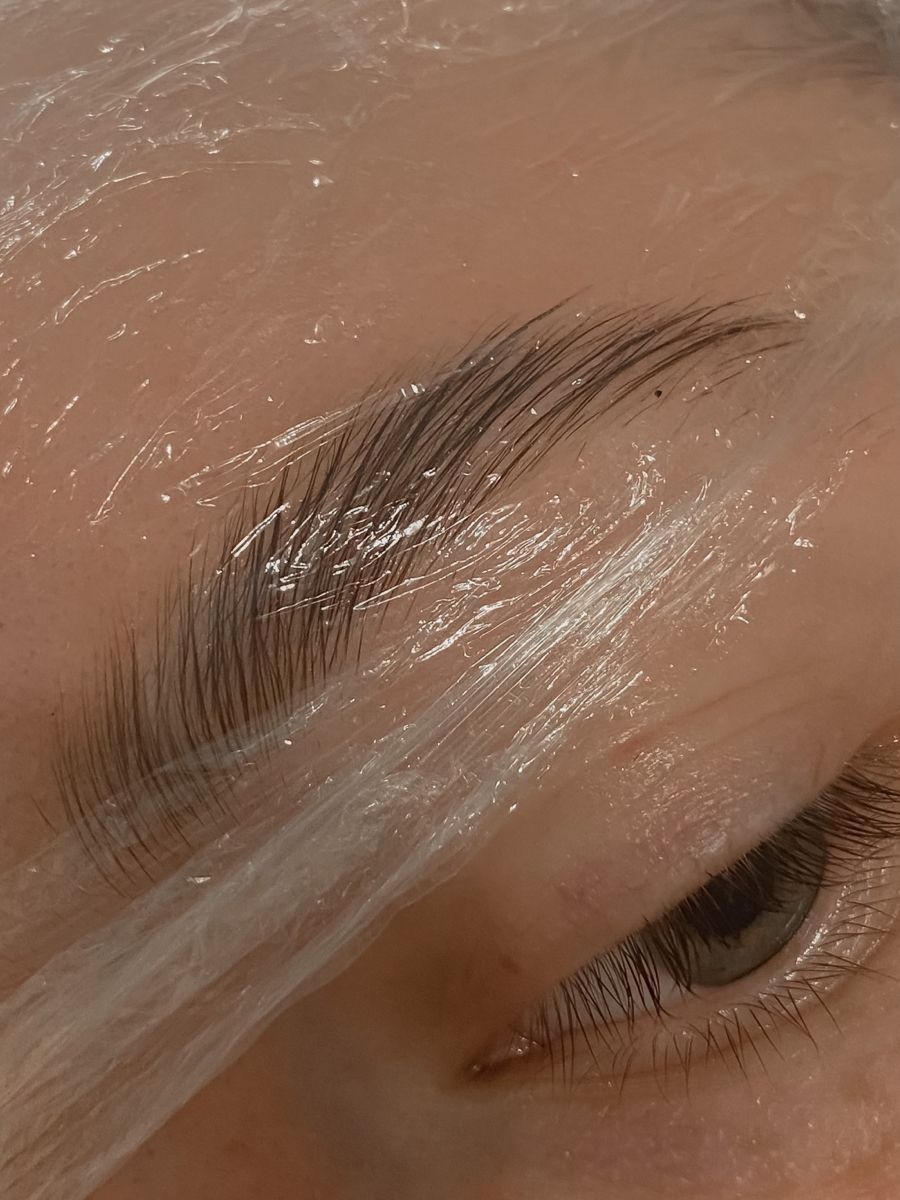A brow mid-lamination, wrapped under film while the treatment sets